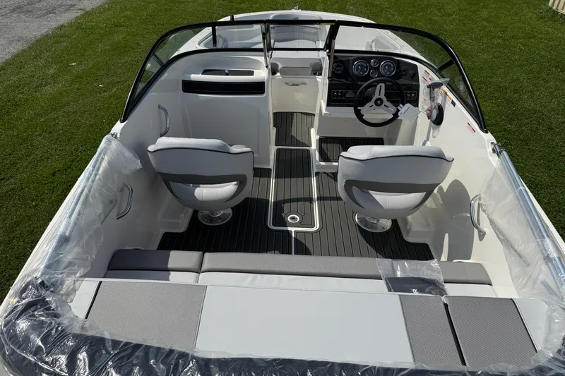 Slide: The Image of 2025 Bayliner VR4 Bowrider I/O interior with seating and steering wheel on grass. - 6