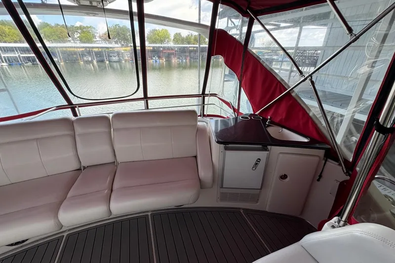 Slide: The Image of 2003 Silverton 410 Sport Bridge interior with white seating and kitchenette, overlooking marina. - 19