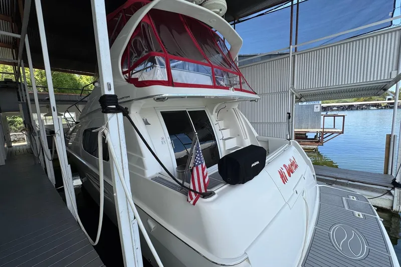 Slide: The Image of 2003 Silverton 410 Sport Bridge yacht docked, featuring red canopy and American flag. - 26