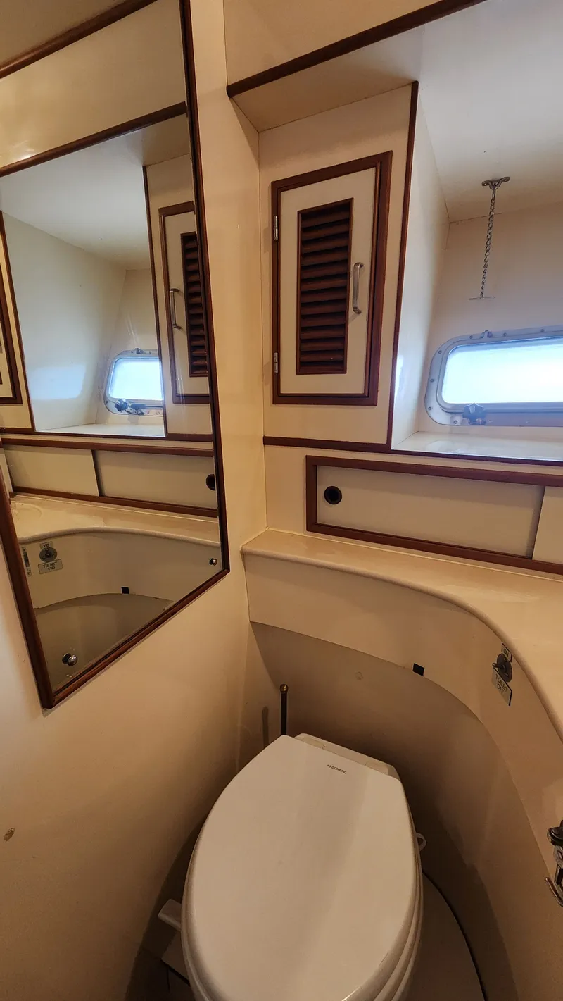 Slide: The Image of 1987 Hi-Star 48 Sundeck yacht bathroom with toilet, mirror, and storage cabinets. - 16