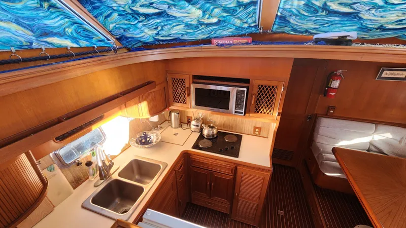 Slide: The Image of 1987 Hi-Star 48 Sundeck yacht interior with kitchen, microwave, stove, and vibrant ceiling design. - 26