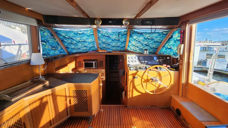 Slide: The Image of 1987 Hi-Star 48 Sundeck interior with wooden helm, nautical decor, and vibrant window coverings. - 34