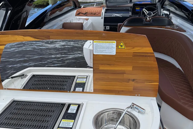 Slide: The Image of 2025 NX Boats NX290 Exclusive interior with wooden accents, grill, and sink. - 11