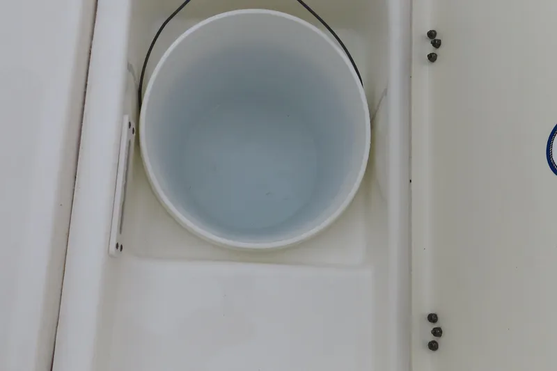 Slide: The Image of 2017 NauticStar 25 XS Offshore boat compartment with a white bucket inside. - 10