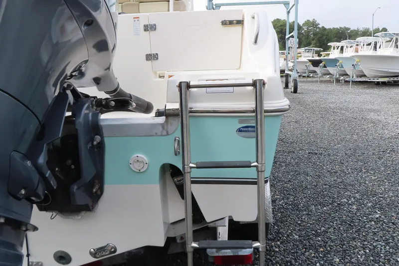 Slide: The Image of 2017 NauticStar 25 XS Offshore boat with ladder and outboard motor, parked on gravel. - 6