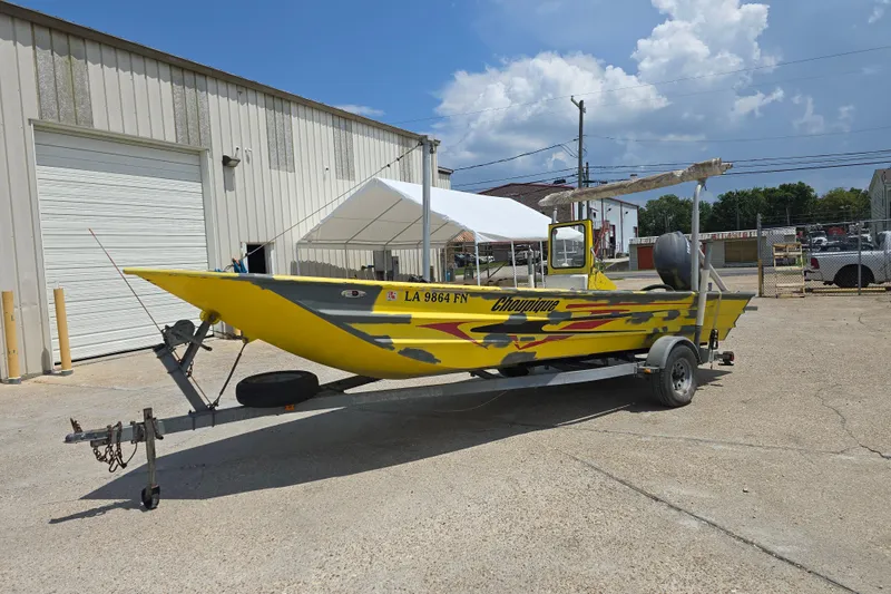 Slide: The Image of Yellow Rookie 22 boat from 2006 on trailer, parked outside industrial building. - 3
