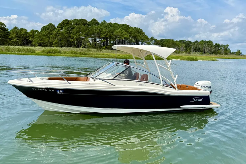 Slide: The Image of 2015 Scout 245 Dorado boat on calm water with scenic forest backdrop. - 1