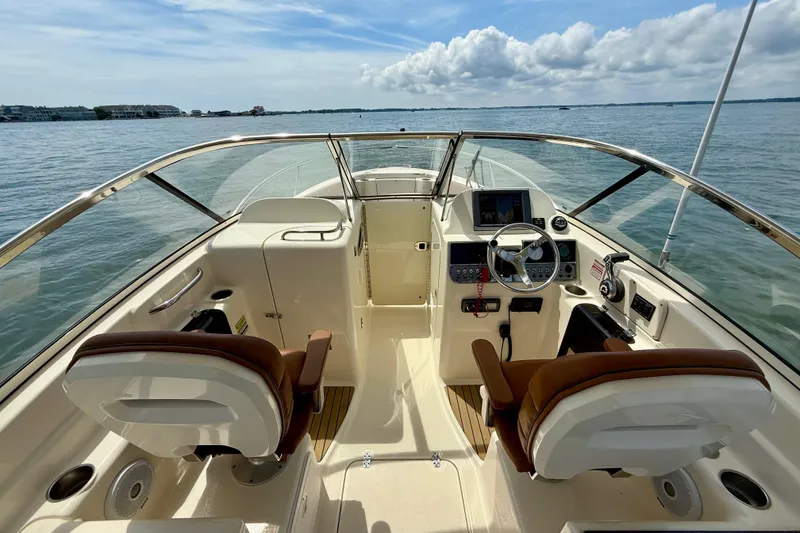 Slide: The Image of 2015 Scout 245 Dorado boat interior with dual seats and steering console on open water. - 16