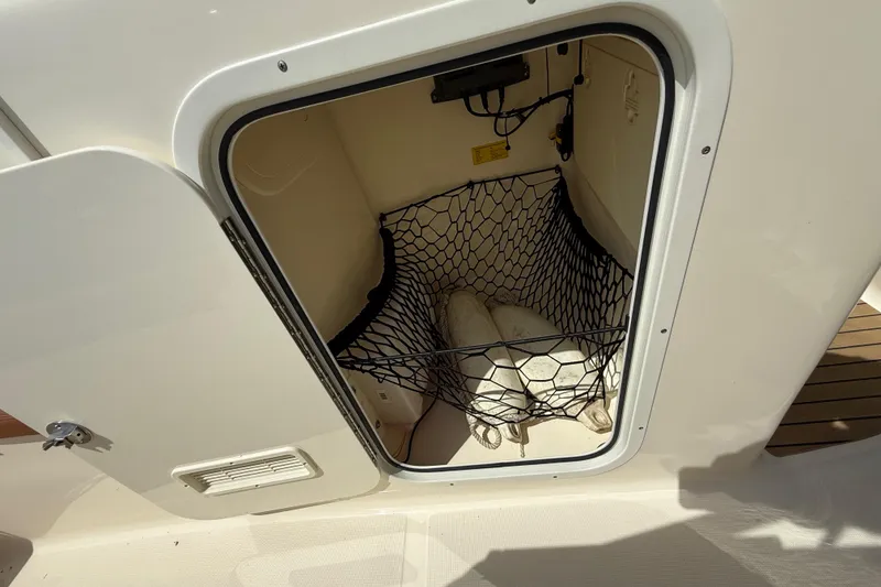 Slide: The Image of Storage compartment on a 2015 Scout 245 Dorado boat with netting and fenders. - 26