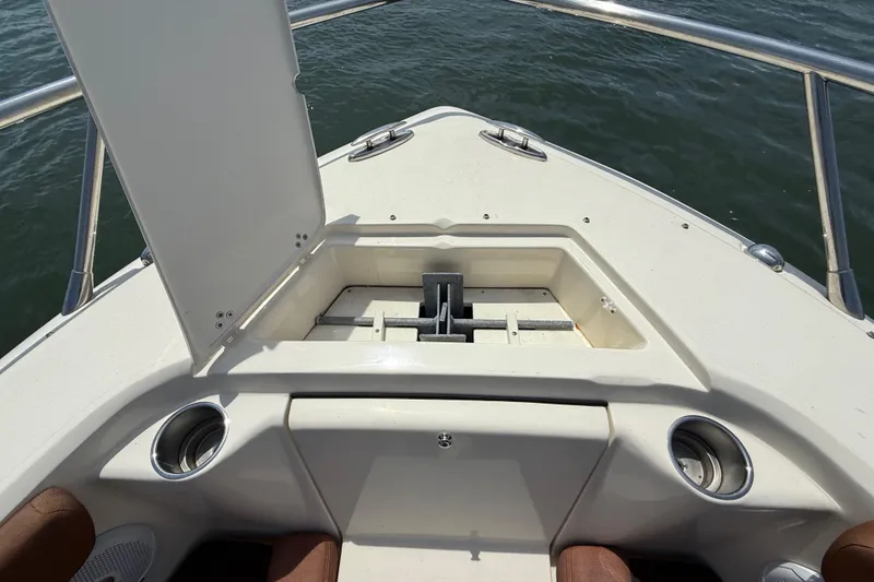 Slide: The Image of 2015 Scout 245 Dorado boat anchor compartment with open hatch, stainless steel railing, and cup holders. - 30
