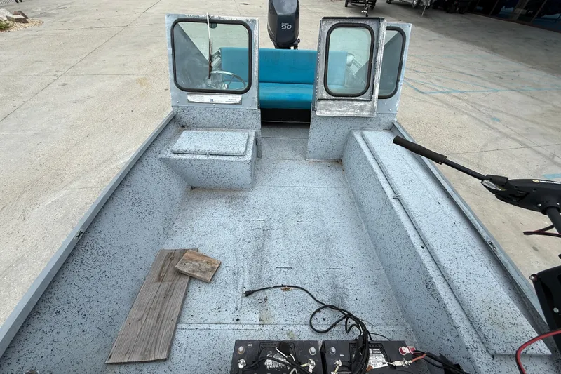 Slide: The Image of 1983 Scully's 16 WT boat interior with blue seating and motor, docked on concrete. - 8