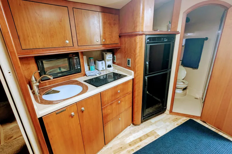 Slide: The Image of 2000 Cruisers Yachts 3870 Express interior kitchen with wood cabinets and appliances. - 19
