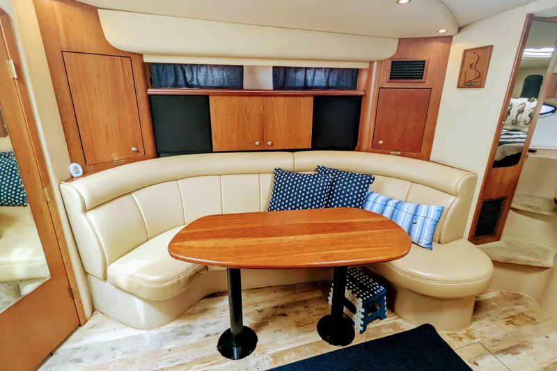 Slide: The Image of Interior of 2000 Cruisers Yachts 3870 Express with curved seating and wooden table. - 23