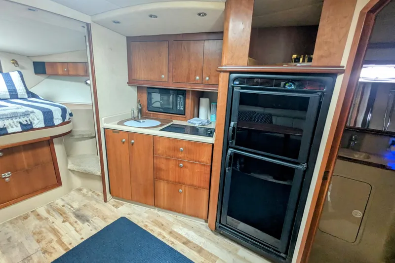 Slide: The Image of 2000 Cruisers Yachts 3870 Express interior with kitchenette, bed, and wooden cabinetry. - 21