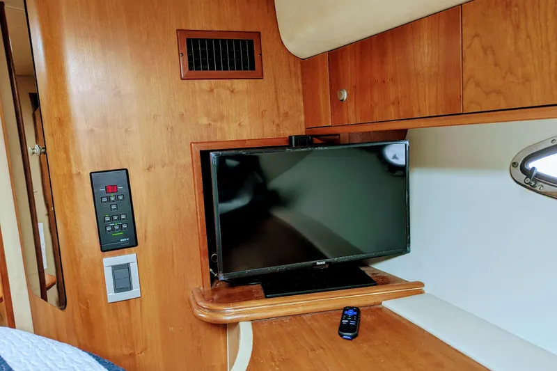 Slide: The Image of Interior of 2000 Cruisers Yachts 3870 Express with TV and remote on wooden surface. - 26