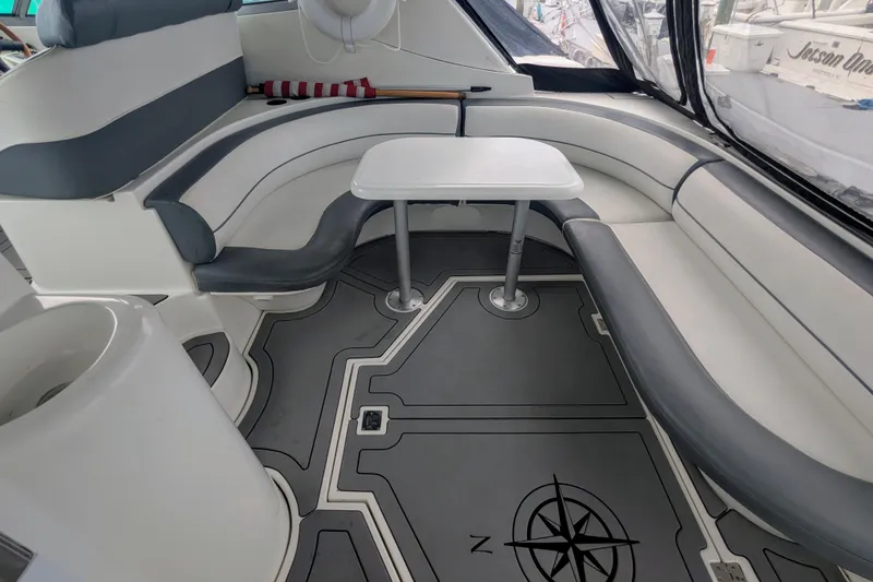 Slide: The Image of 2000 Cruisers Yachts 3870 Express interior with curved seating and table, featuring nautical-themed flooring. - 9