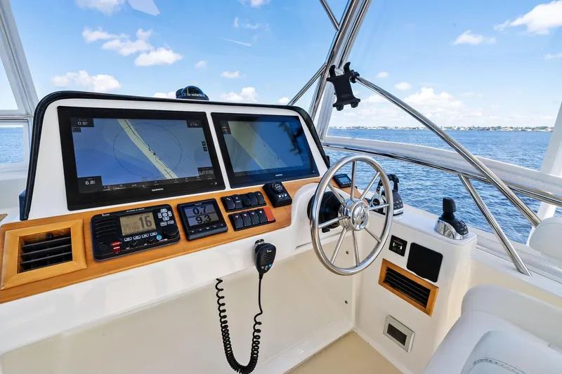 Slide: The Image of 2019 Sabre Flybridge helm with dual navigation screens and steering wheel, overlooking ocean. - 19
