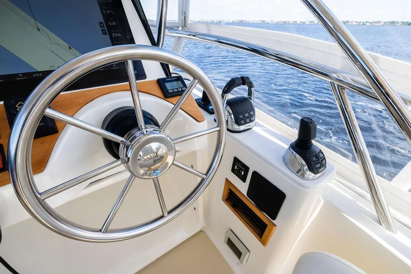 Slide: The Image of 2019 Sabre Flybridge helm with steering wheel and controls, overlooking the ocean. - 21