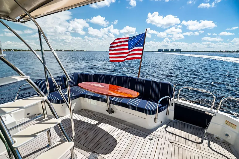 Slide: The Image of 2019 Sabre Flybridge yacht deck with seating, American flag, and ocean view. - 24