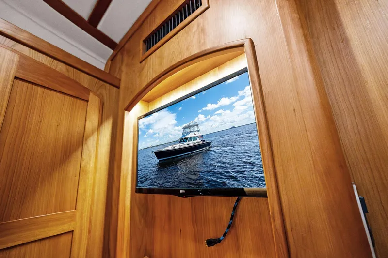 Slide: The Image of Wall-mounted TV displaying a Sabre Flybridge yacht, 2019 model, in a wooden interior. - 30