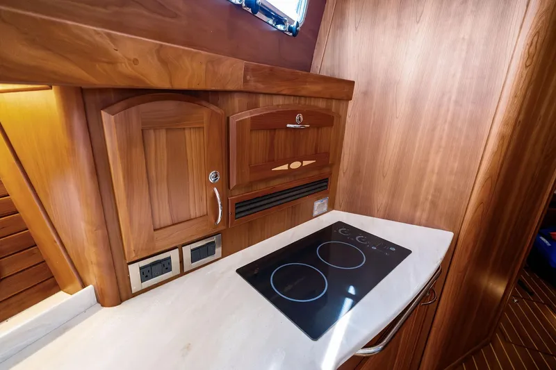 Slide: The Image of 2019 Sabre Flybridge yacht kitchen with wooden cabinetry and modern stovetop. - 35