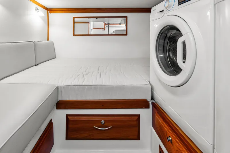 Slide: The Image of 2019 Sabre Flybridge interior with bed, washing machine, and wooden drawers. - 43