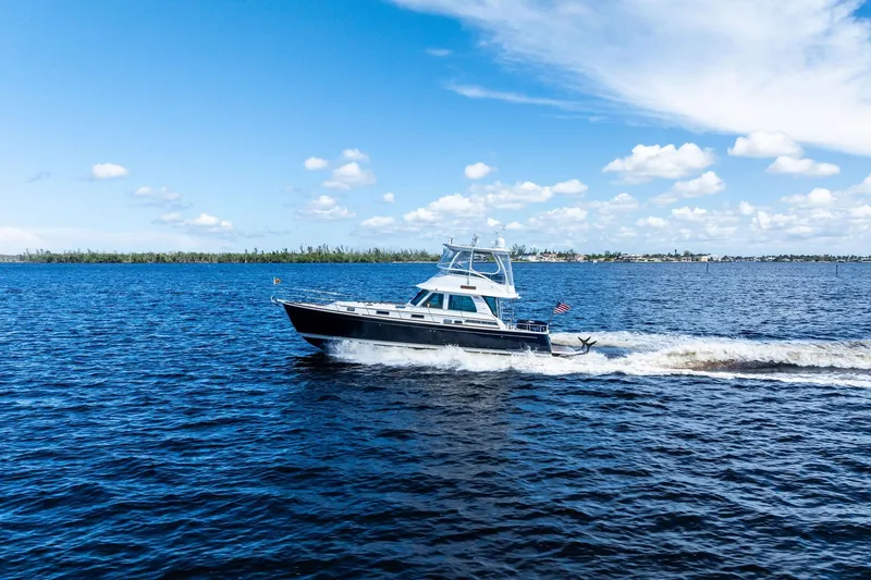Slide: The Image of 2019 Sabre Flybridge cruising on open water under a clear blue sky. - 62