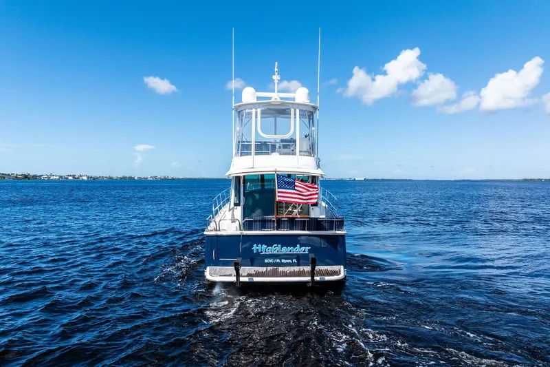 Slide: The Image of 2019 Sabre Flybridge yacht on open water, American flag displayed, clear blue sky. - 72