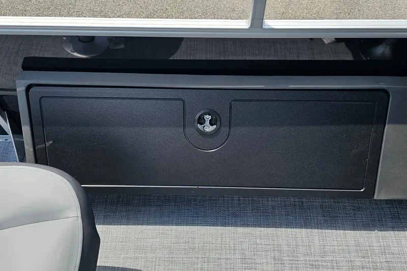 Slide: The Image of 2026 Sun Tracker Sportfish 24 XP3 storage compartment with lock, gray interior. - 17