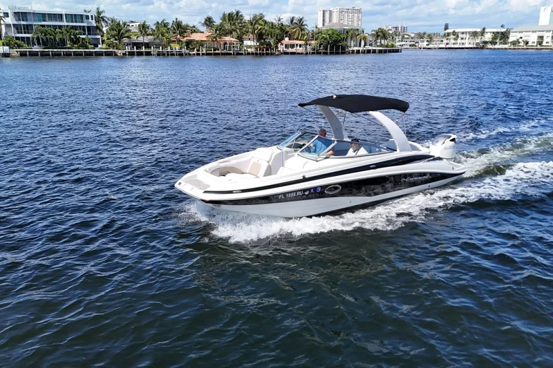 The Image of 2020 Crownline 24 boat cruising on a sunny day near waterfront homes. - 1
