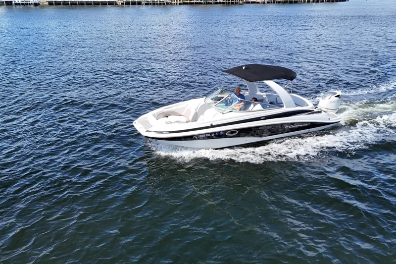 Slide: The Image of 2020 Crownline 24 boat cruising on open water with passengers under a black canopy. - 10