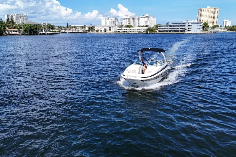 Slide: The Image of 2020 Crownline 24 boat cruising on a sunny day near city skyline. - 11