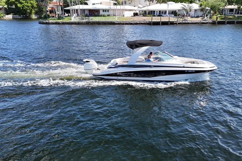 Slide: The Image of 2020 Crownline 24 boat cruising on a sunny day near waterfront homes. - 12