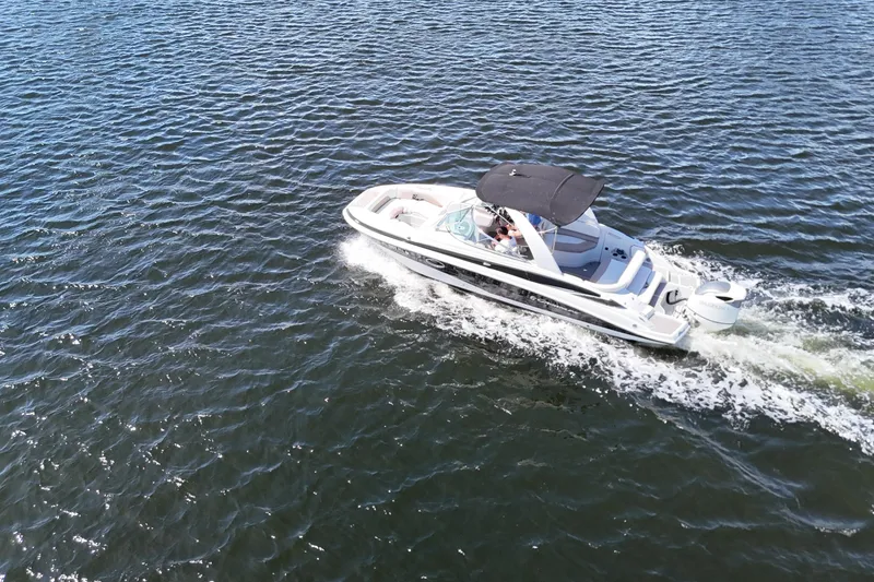 Slide: The Image of 2020 Crownline 24 boat cruising on open water with a black canopy. - 19