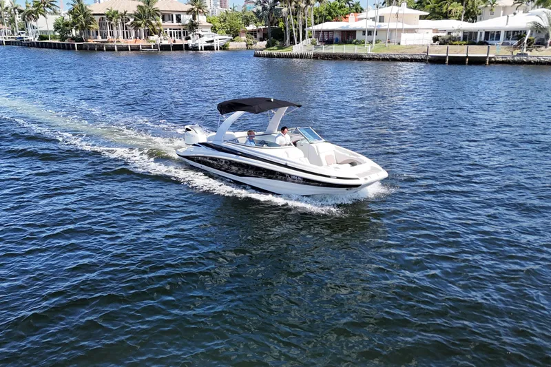Slide: The Image of 2020 Crownline 24 boat cruising on a sunny waterway with waterfront homes. - 2