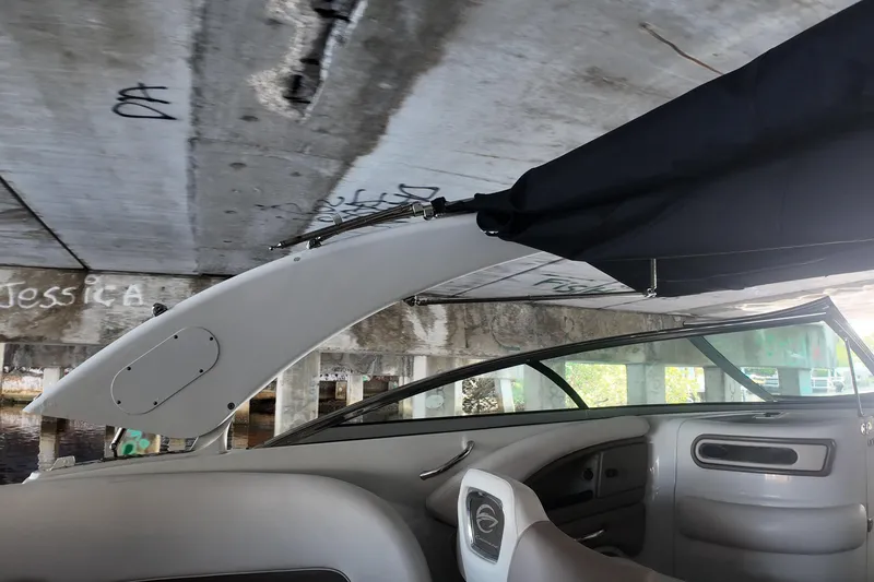 Slide: The Image of 2020 Crownline 24 boat interior under bridge with graffiti, featuring sleek design and canopy. - 25
