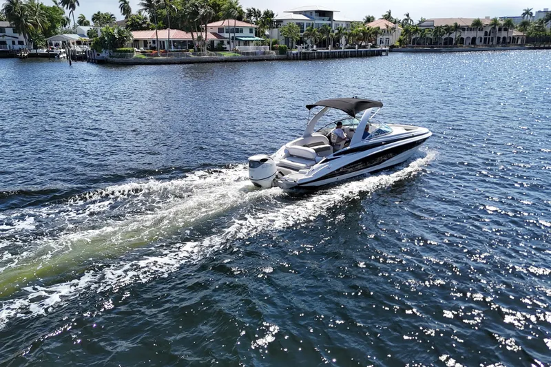 Slide: The Image of 2020 Crownline 24 boat cruising on a sunny waterfront with luxury homes in the background. - 3