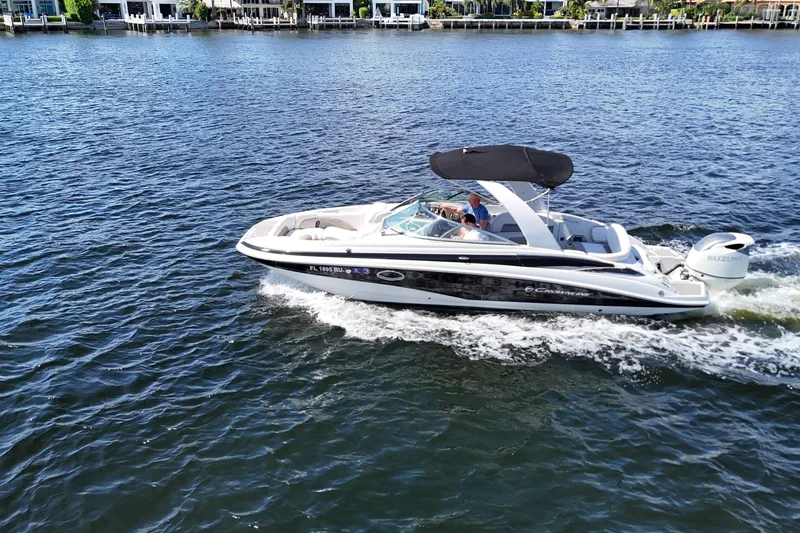 Slide: The Image of 2020 Crownline 24 boat cruising on a sunny day with waterfront homes in the background. - 9
