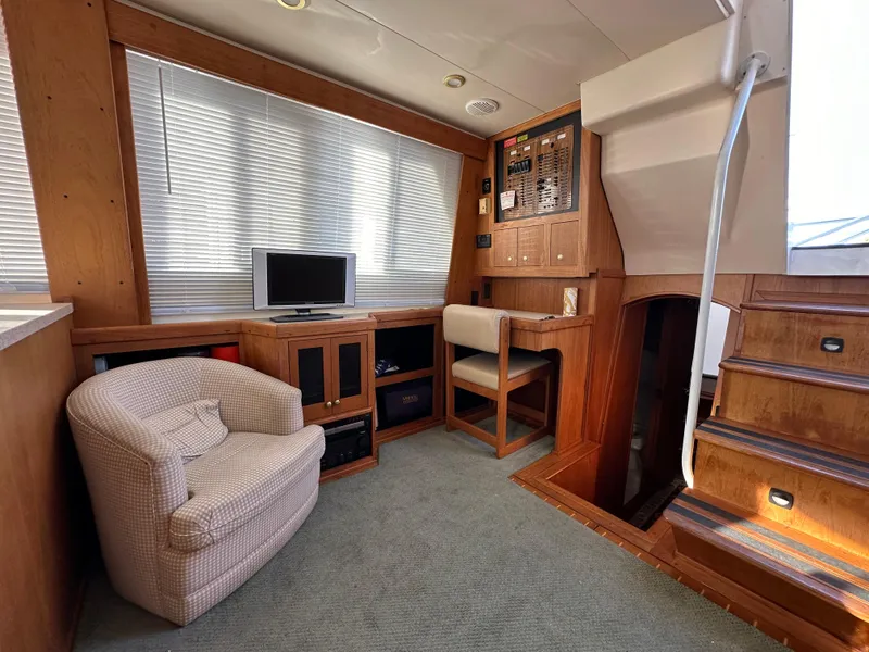 Slide: The Image of Mainship 43 Trawler Aft Cabin interior, featuring cozy seating, TV, and wooden cabinetry, 2000 model. - 11