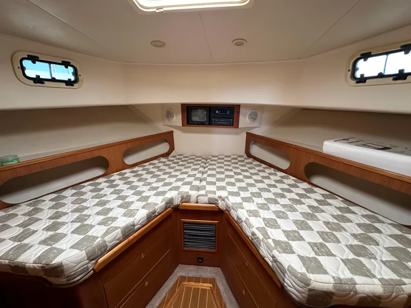 Slide: The Image of 2000 Mainship 43 Trawler Aft Cabin interior with checkered bedding and wooden storage. - 12