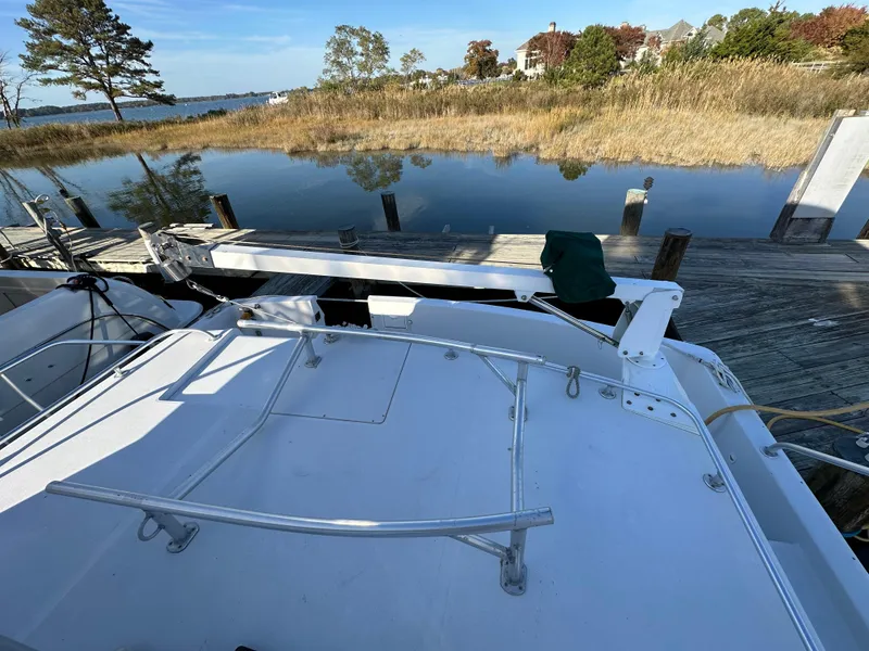 Slide: The Image of 2000 Mainship 43 Trawler Aft Cabin docked by a serene waterfront with trees. - 15
