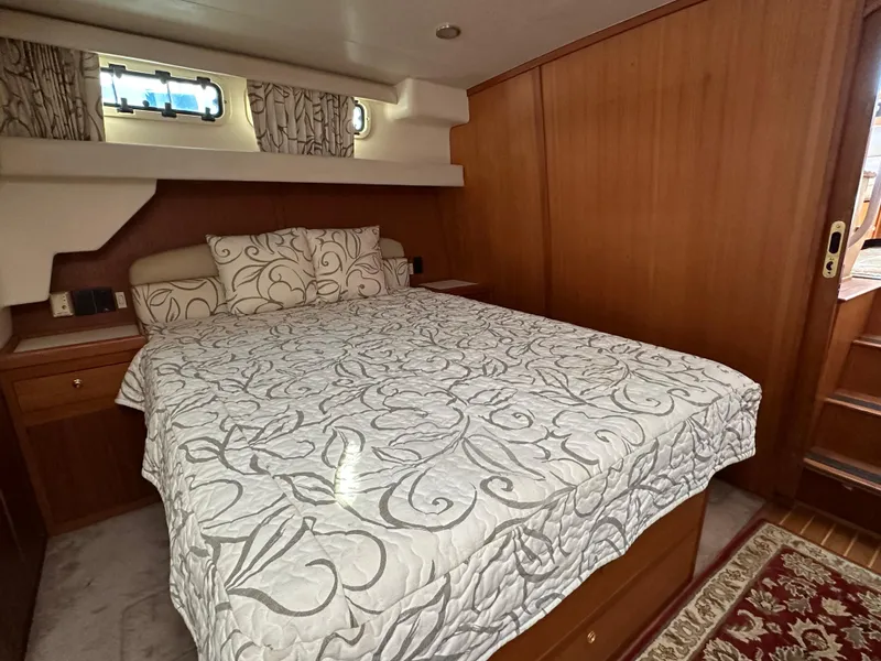 Slide: The Image of Aft cabin bedroom in 2000 Mainship 43 Trawler with elegant bedding and wooden interior. - 21