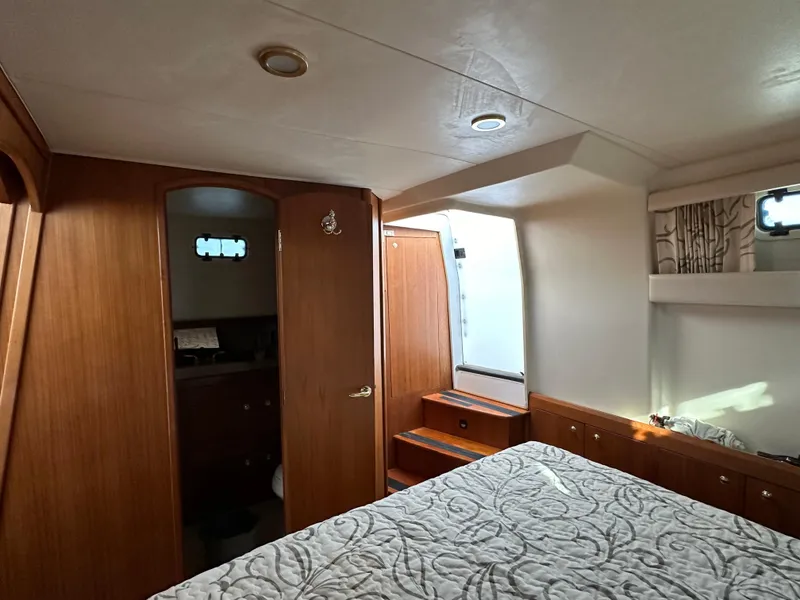 Slide: The Image of Aft cabin interior of 2000 Mainship 43 Trawler, featuring wood paneling and a cozy bed. - 22