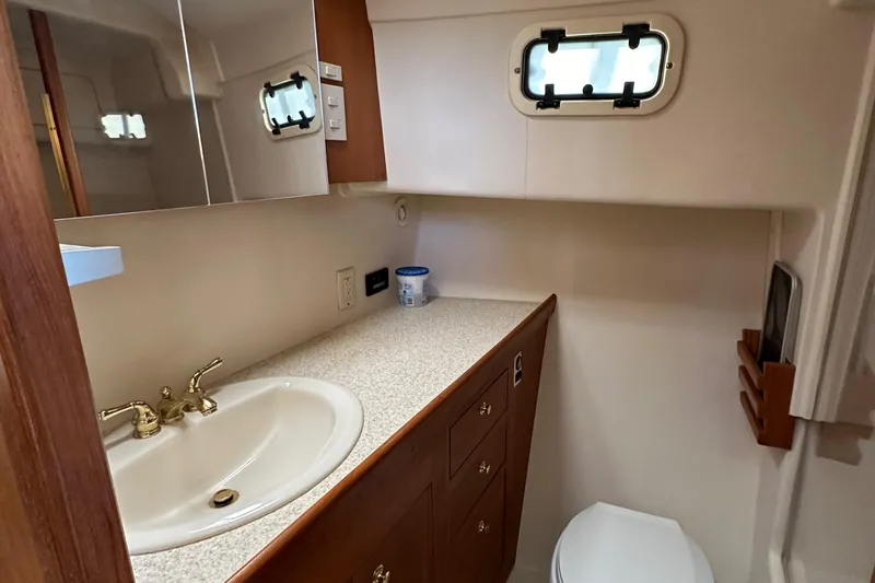 Slide: The Image of Bathroom in 2000 Mainship 43 Trawler Aft Cabin with sink, toilet, and storage cabinets. - 24
