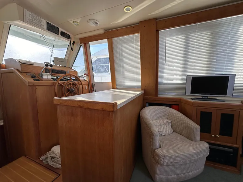 Slide: The Image of Interior of 2000 Mainship 43 Trawler Aft Cabin with helm, chair, and TV. - 9