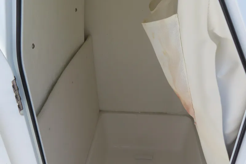 Slide: The Image of Interior storage compartment of 2019 Sea Hunt Ultra 225 boat, featuring white walls and curtain. - 20