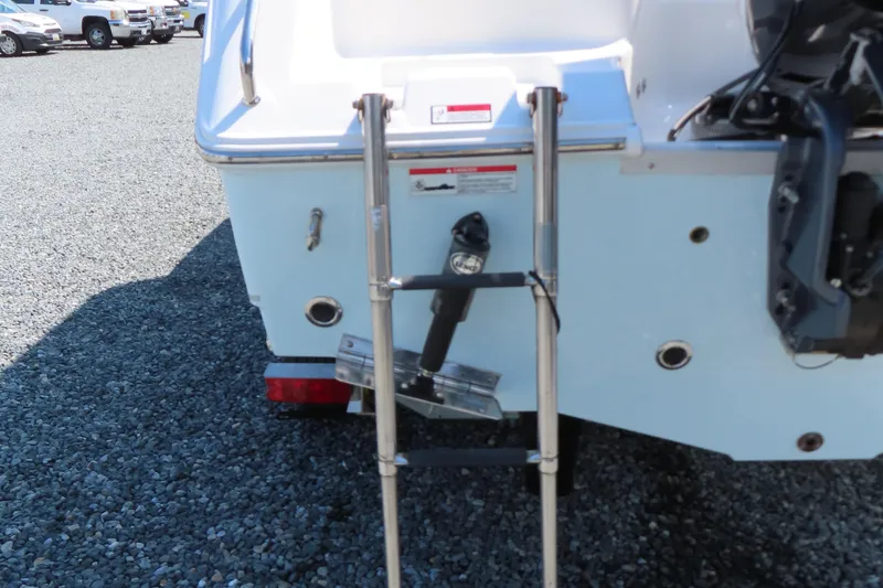 Slide: The Image of 2019 Sea Hunt Ultra 225 boat with rear ladder on gravel surface. - 6