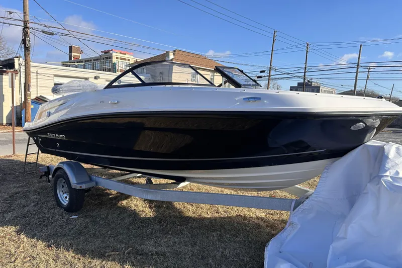 Slide: The Image of 2025 Bayliner VR5 Bowrider OB on trailer, parked outdoors under clear blue sky. - 2