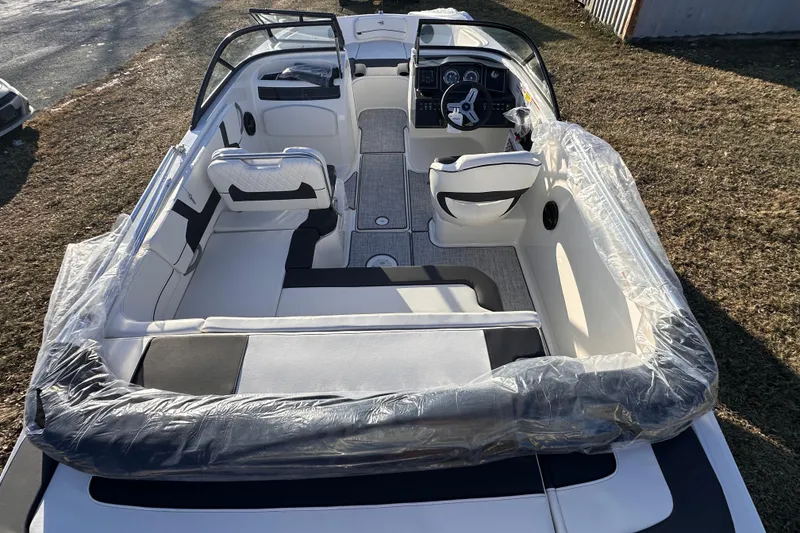 Slide: The Image of 2025 Bayliner VR5 Bowrider OB interior with seating and steering wheel, parked on grass. - 5