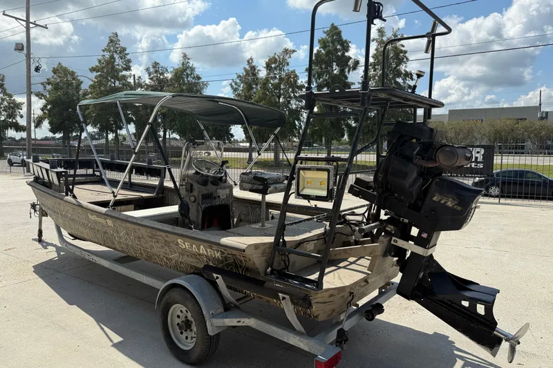 Slide: The Image of 2016 SeaArk 180 Mudrunner boat on trailer, featuring camouflage design and canopy. - 4